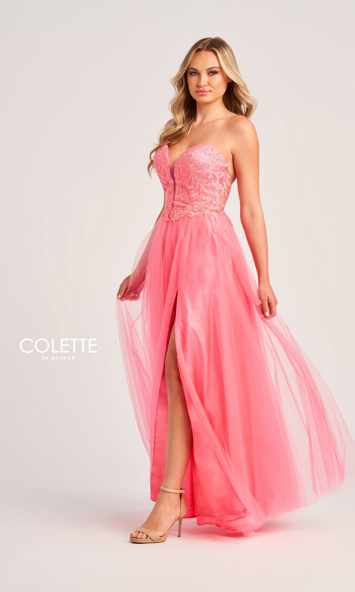 A woman poses against a light background in the elegant Colette Strapless Long A-Line Prom Dress CL5132, featuring pink lace, tulle, a strapless neckline, and a high slit. The word
